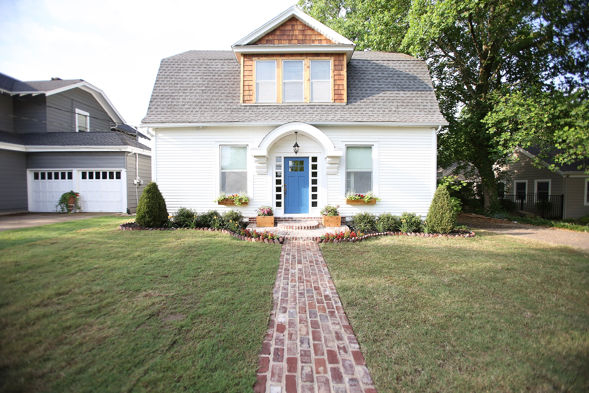Reclaimed brick walkway lead to a home exterior with cedar shingle dormer.