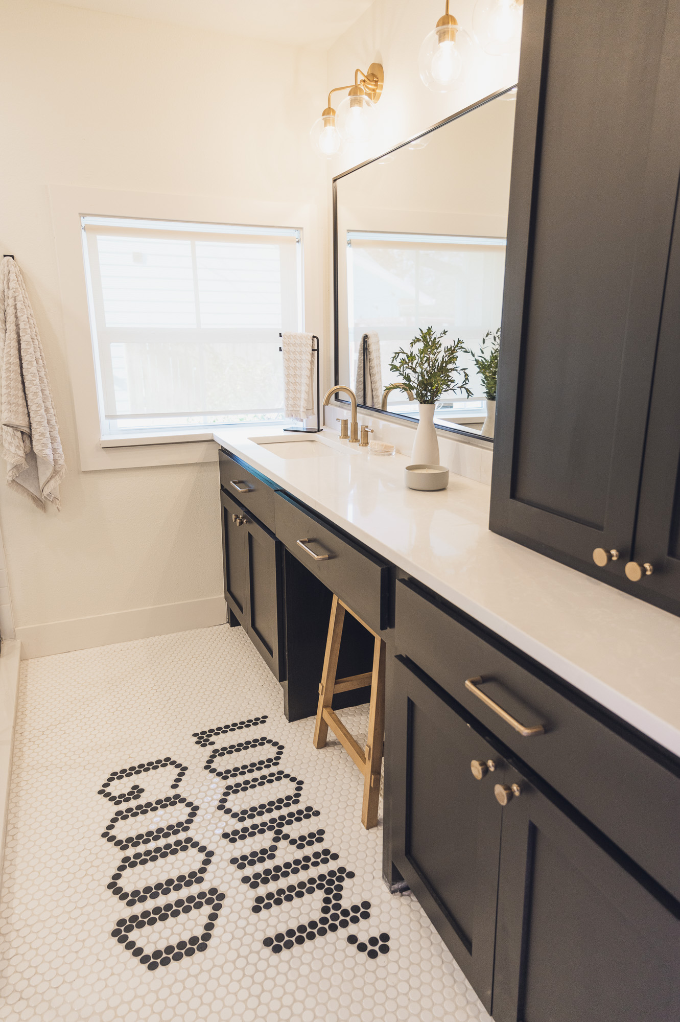Bathroom with dark cabinetry, window, and penny tile