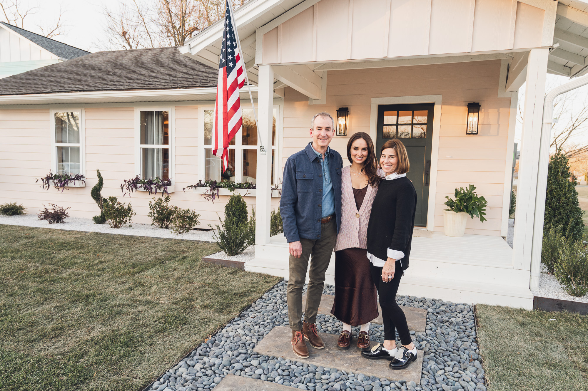 Bowman Cooper and her parents standing in front of her light pink, renovated house.