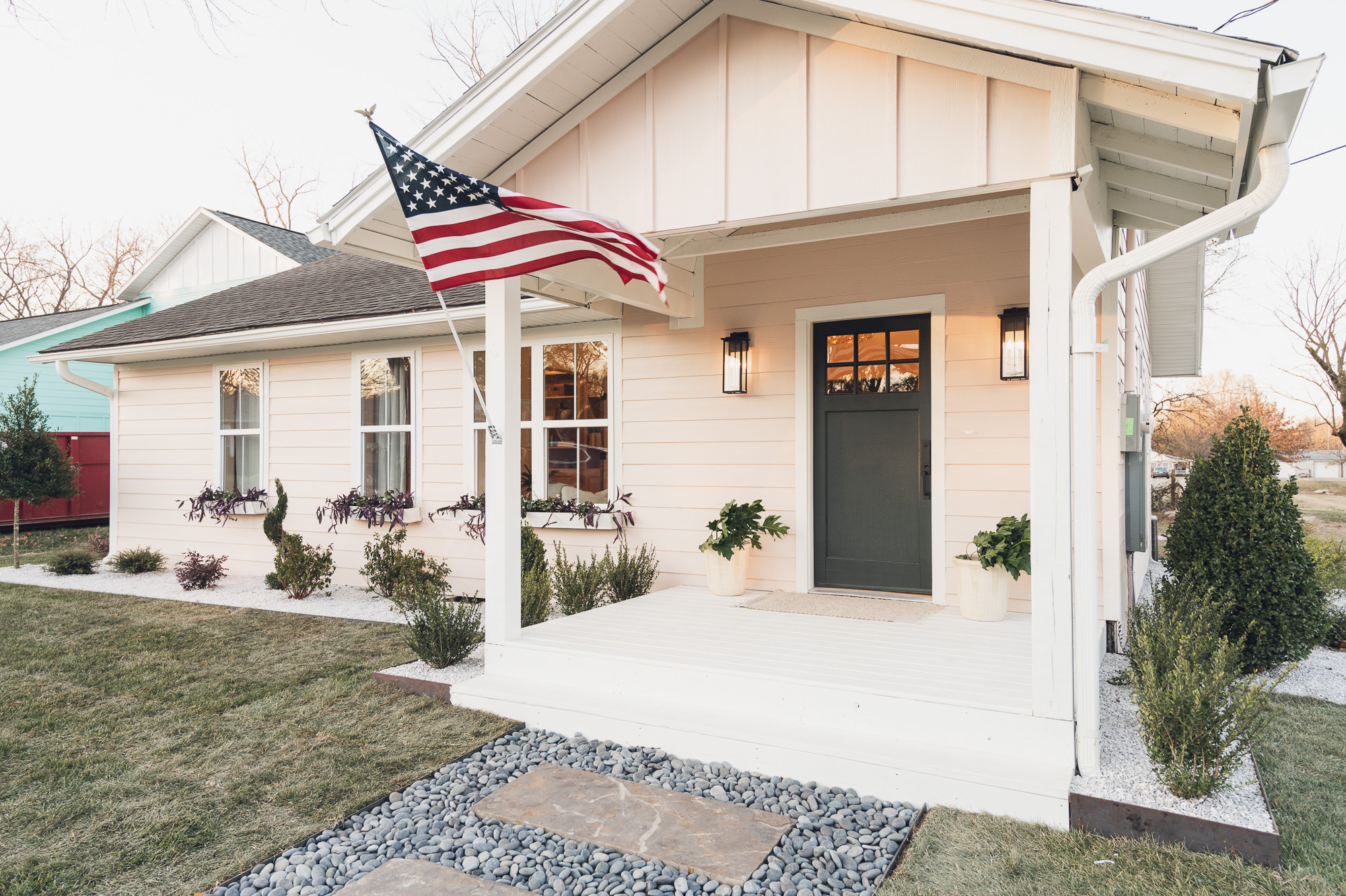 Light pink house with dark door and American flag on porch