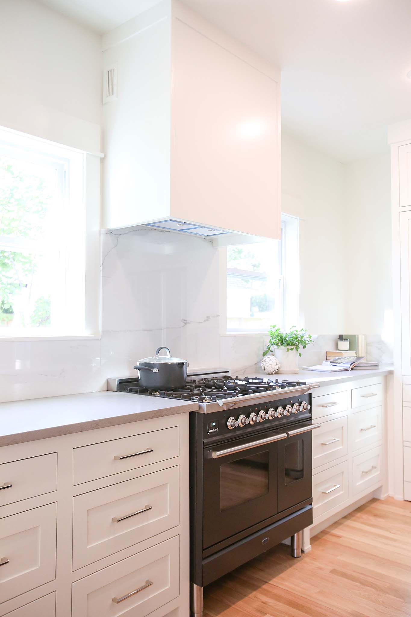 Kitchen renovation with large vent hood and white cabinets on HGTV Fixer to Fabulous.